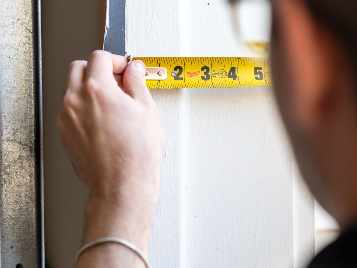 Contractor measuring a door opening with a tape measure