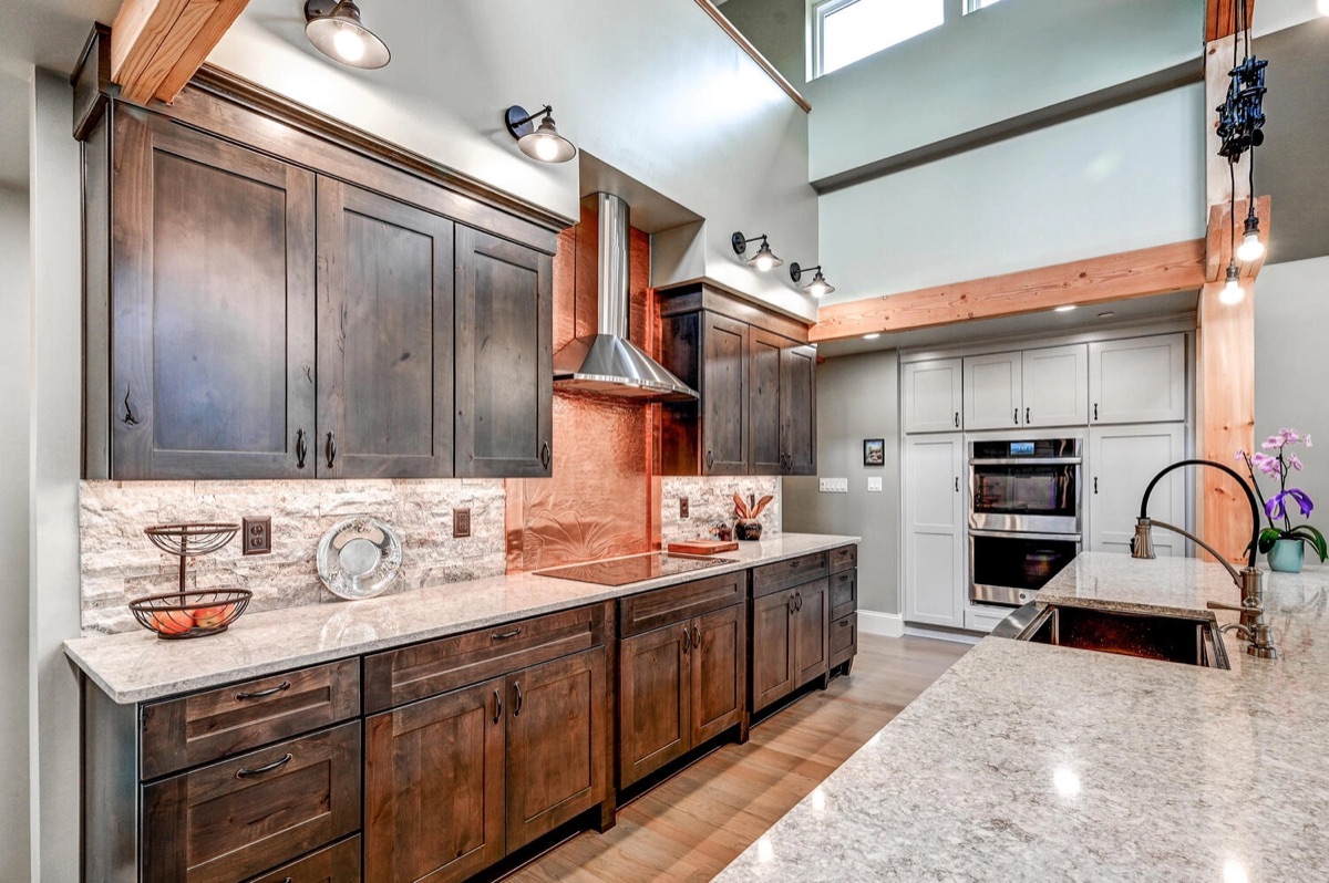 Stained natural wood kitchen cabinets with a stone backsplash